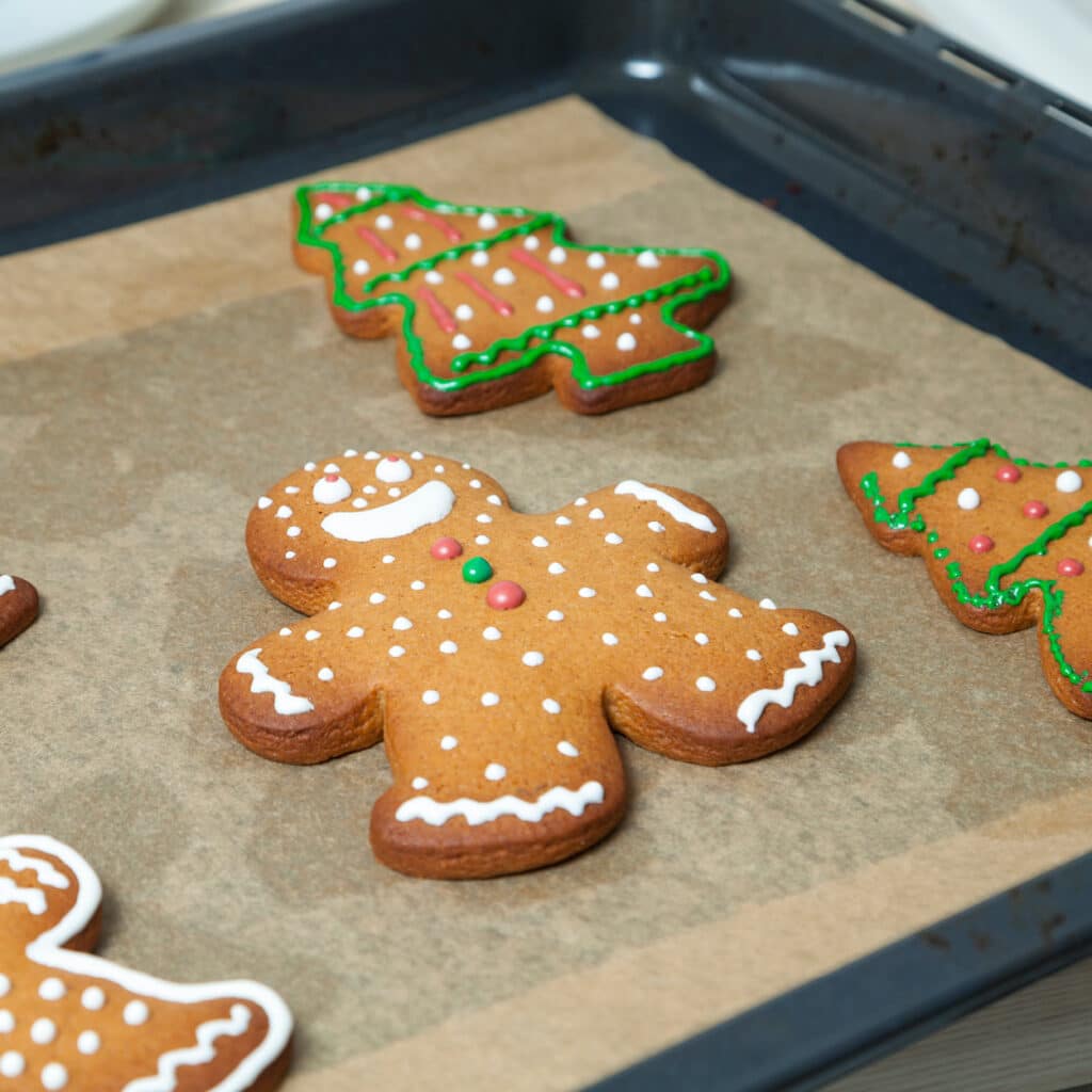 Lebkuchenmann und Tannenbaum-Plätzchen mit bunter Glasur auf dem Backblech.