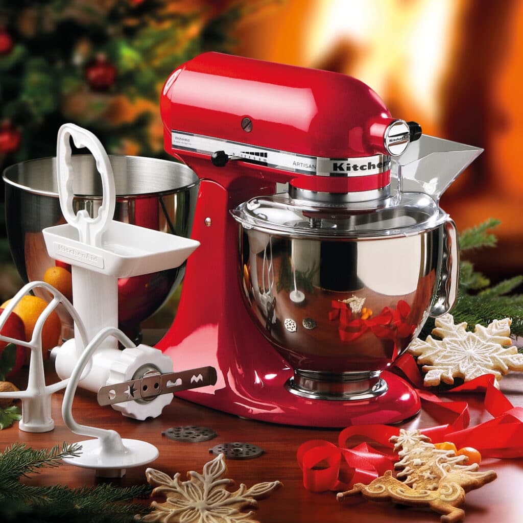 Rote KitchenAid Küchenmaschine mit Edelstahl-Schüssel, Fleischwolfaufsatz und weihnachtlichen Ausstechformen.