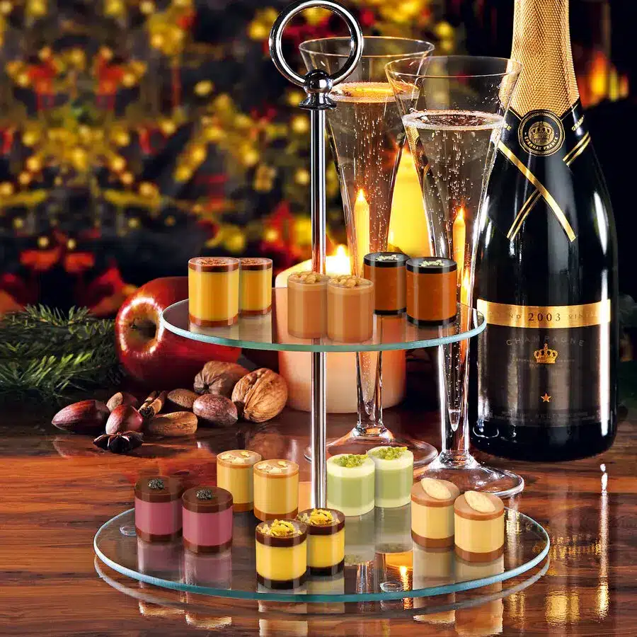 Edle Pralinen-Auswahl auf Glasetagere mit Sekt und Kerzenschein, verfeinert mit Pistazien, Karamell und Schokolade