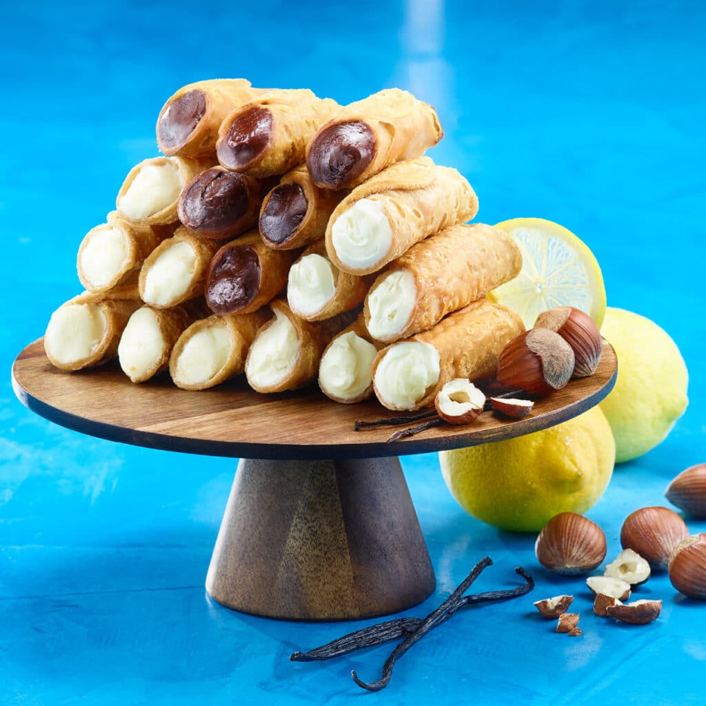 Knusprige Cannoli mit Vanille-, Schokoladen- und Zitronencreme, italienisches Gebäck auf Holzständer
