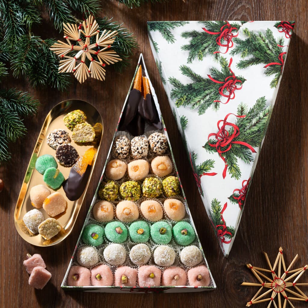 Geschenkbox in Tannenbaumform, gefüllt mit farbigem Konfekt, Marzipan und Pralinen, festlich dekoriert